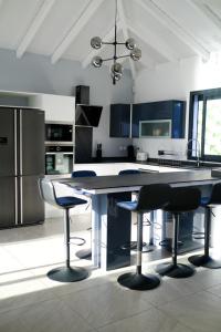 a kitchen with a table and three bar stools at La villa O'rizon in Le Diamant