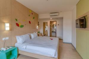 1 dormitorio con cama blanca y pared en Ascent Hotel & Cafe Malang, en Malang