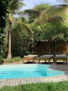 a swimming pool with two benches and a picnic table at Terraza Salvatore, Casa en Las Pocitas de Máncora in Máncora