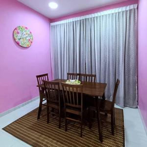 una sala da pranzo con pareti rosa e tavolo e sedie di Ebnur Homestay ad Arau