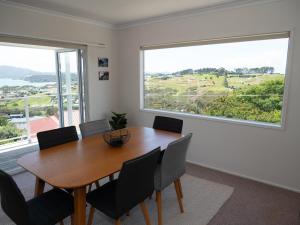 a dining room with a table and chairs and a large window at Fun in the Sun in Cable Bay