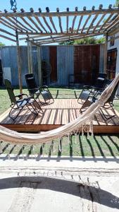 2 sillas y una hamaca en una terraza de madera en Casa de Campo, con Pileta y Asador Criollo!! - "La Ranchada" en Gualeguaychú