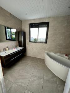 a bathroom with a tub and a sink and a bath tub at La villa O'rizon in Le Diamant