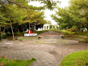 Emersia Hotel & Resort Batusangkar في Batusangkar: موقف مع مقاعد وعلامة في الخلفية