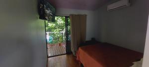 Zimmer mit einem Bett und einer Tür mit einem Fenster in der Unterkunft ENCANTADORA CABAÑA DEL BOSQUE in San José