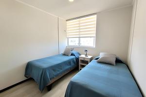 dwa łóżka w pokoju z oknem w obiekcie Condominio Pacífico 3100 w mieście La Serena