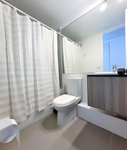 Baño blanco con aseo y lavamanos en Condominio Pacífico 3100, en La Serena