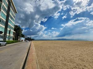 an empty beach with a building and a cloudy sky at D@Sea Hotel in Jomtien Beach