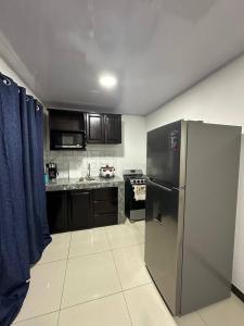 una cocina con nevera de acero inoxidable y armarios negros en Twoanis Apartment, en Tambor