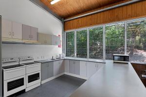 a large kitchen with white appliances and windows at Kipara Tropical Rainforest Retreat in Airlie Beach