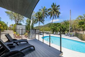 a deck with chairs and a swimming pool at Kipara Tropical Rainforest Retreat in Airlie Beach
