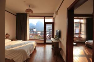 Schlafzimmer mit einem Bett und Blick auf einen Balkon in der Unterkunft Yangshuo Xiao Long River Hotel in Yangshuo