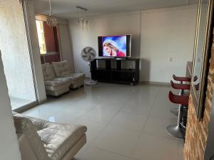 uma sala de estar com uma televisão de ecrã plano e um sofá em Apartamento cerca a zonas exclusivas de Barranquilla em Barranquilla