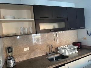 a kitchen counter with a sink and black cabinets at Apartamento cerca a zonas exclusivas de Barranquilla in Barranquilla