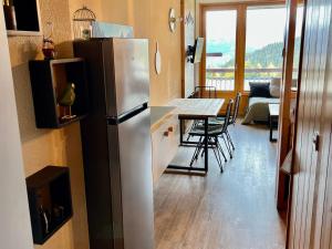 a kitchen with a refrigerator and a table with chairs at Studio ski aux pieds avec balcon et fibre, 5 pers - FR-1-346-555 in Arc 1800