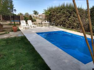 a blue swimming pool with two chairs and a table at Casa Martín in Tunuyán