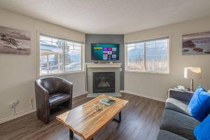 a living room with a couch a table and a tv at B211 MTN View ground floor town house- 2BD, Sleeps 8, hot tub, free parking, close to Banff in Canmore