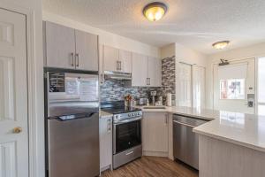 eine Küche mit einem Kühlschrank und Schränken aus Edelstahl in der Unterkunft B211 MTN View ground floor town house- 2BD, Sleeps 8, hot tub, free parking, close to Banff in Canmore