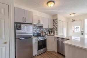 a kitchen with a stainless steel refrigerator and cabinets at B211 MTN View ground floor town house- 2BD, Sleeps 8, hot tub, free parking, close to Banff in Canmore