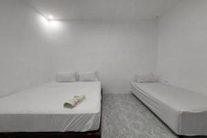 2 camas en una habitación con paredes blancas en Residence Syariah, en Binjai