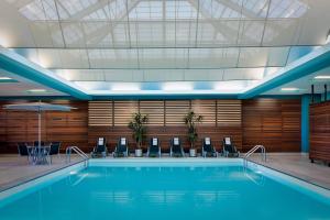 a swimming pool in a hotel with chairs and an umbrella at Courtyard Grand Rapids Downtown in Grand Rapids