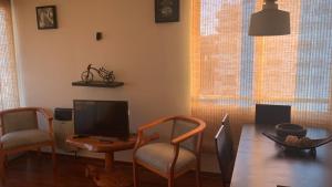 sala de estar con mesa, sillas y TV en ACOGEDOR DEPARTAMENTO VIÑA PLAZA 6, en Viña del Mar