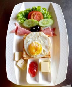 a white plate with an egg on toast with cheese and fruit at Benny's City Hotel in Sihanoukville