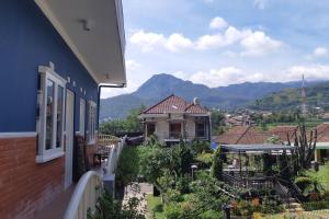 einen Blick auf ein Haus mit Bergen im Hintergrund in der Unterkunft Sekar Gambir Homestay in Batu
