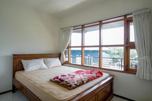 Bett in einem Zimmer mit einem großen Fenster in der Unterkunft Sekar Gambir Homestay in Batu