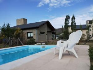 a pair of white chairs sitting next to a swimming pool at HolaViajerosVGB in Villa General Belgrano