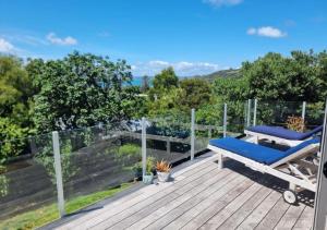 um deque com uma cadeira azul em cima em Tiri Cottage - Sea Views in Oneroa by Waiheke Unlimited em Oneroa