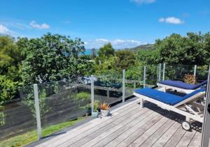 a deck with a blue chair on top of it at Tiri Cottage - Sea Views in Oneroa by Waiheke Unlimited in Oneroa