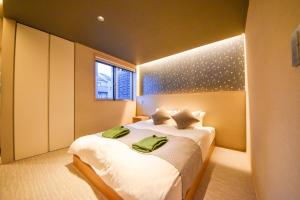 Hotel Rokune في نارا: غرفة نوم بسرير كبير عليها مناشف خضراء