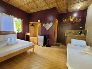 two beds in a room with purple walls at Cecilia's Guest House in Siquijor