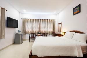 een slaapkamer met een groot wit bed en een tafel bij Hoang Hoang Hotel (Bloom 3) in Ho Chi Minh-stad