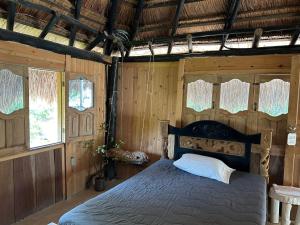 1 dormitorio con 1 cama en una habitación con paredes de madera en Punta Arena EcoHostal & EcoFit, en Playa Punta Arena