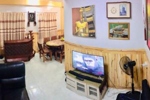 a living room with a tv on a stand with a table at Baguio Exotic Vacation House in Baguio