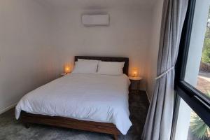 Serenity View Studio Retreat في Woombye: غرفة نوم مع سرير مع مصباحين على طاولتين
