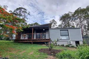 a tiny house with a large deck on a yard at Serenity View Studio Retreat in Woombye