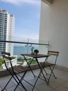 una mesa y sillas en un balcón con vistas al océano en Southbay Seaview Condo A16 #10minQueensbay #15minSPICE, en Bayan Lepas