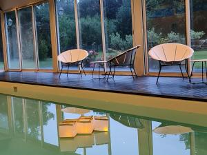 two chairs and a table on a porch with a reflection in the water at La Suite Mucha - Manoir des Marronniers VI in Sully