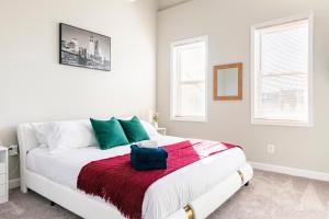 a white bedroom with a bed with green and red blanket at Spacious, Relaxing & Gorgeous 4BD/4BA House in DC! in Washington, D.C.