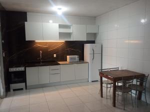 a kitchen with a table and a white refrigerator at Casa em Mongaguá, próximo a Plataforma de Pesca in Mongaguá