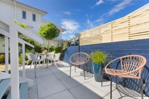 a patio with chairs and a table and a fence at Omanu Cottage in Mount Maunganui