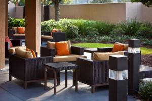 un patio con sillas de mimbre y mesas con almohadas de color naranja en Courtyard Baton Rouge Siegen Lane en Baton Rouge