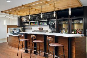 a kitchen with a bar with stools at Courtyard Baton Rouge Siegen Lane in Baton Rouge
