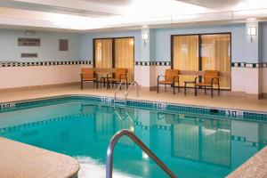 a pool in a hotel room with chairs and tables at Courtyard Baton Rouge Siegen Lane in Baton Rouge
