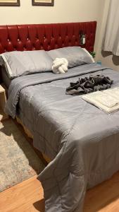 Bett mit einem roten Kopfteil und einem Bademantel. in der Unterkunft Quarto área central zona 04 in Maringá