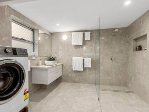 a bathroom with a washing machine and a shower at Sutherland Sunrise in Kingscliff