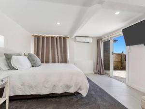 a white bedroom with a bed and a large window at Sutherland Sunrise in Kingscliff
